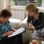 Dos mujeres conversan y revisan juntas los materiales del proyecto «¡Tengo un Plan! Vivir bien con problemas de memoria».