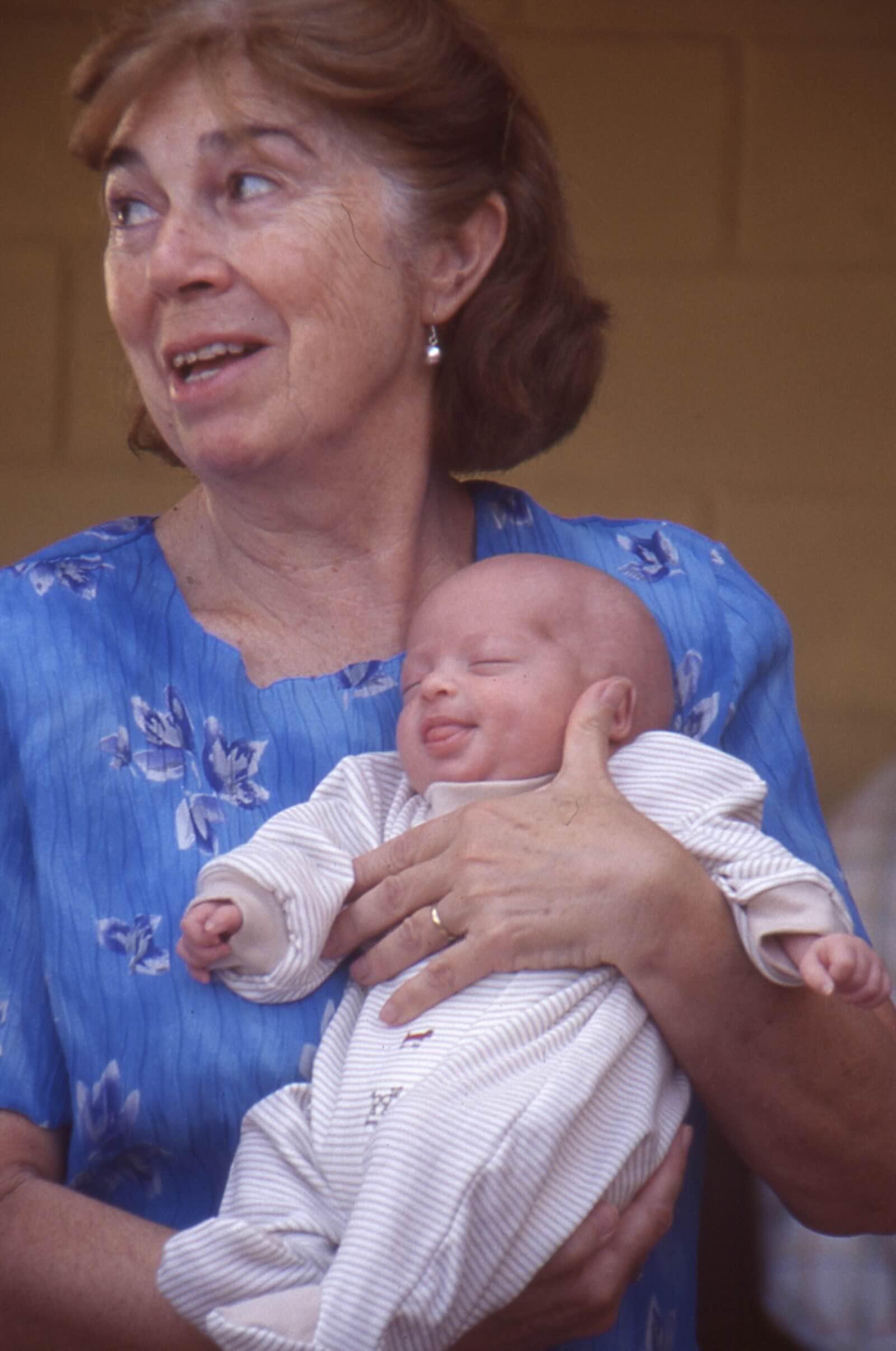 Mujer mayor sosteniendo a un bebé en brazos, reflejo de la calidad de vida basada en las relaciones, el cuidado y la continuidad entre generaciones.